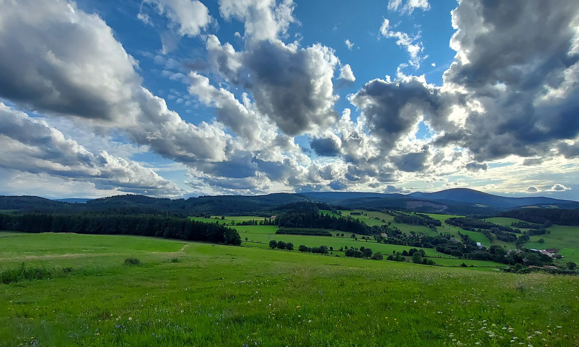 Panorama Karkonoszy z zielonymi łąkami i chmurami nad górami