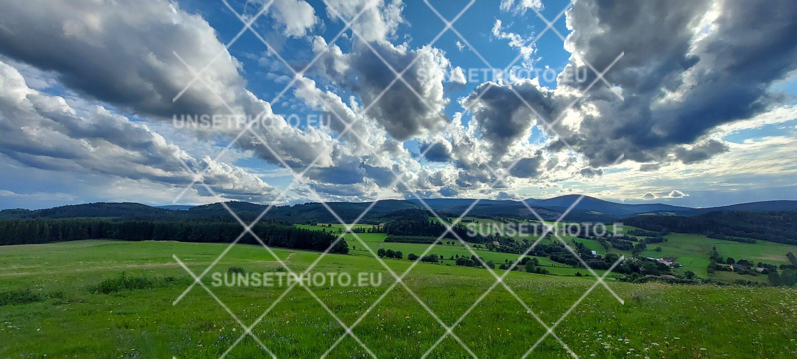 Panorama Karkonoszy z zielonymi łąkami i chmurami nad górami