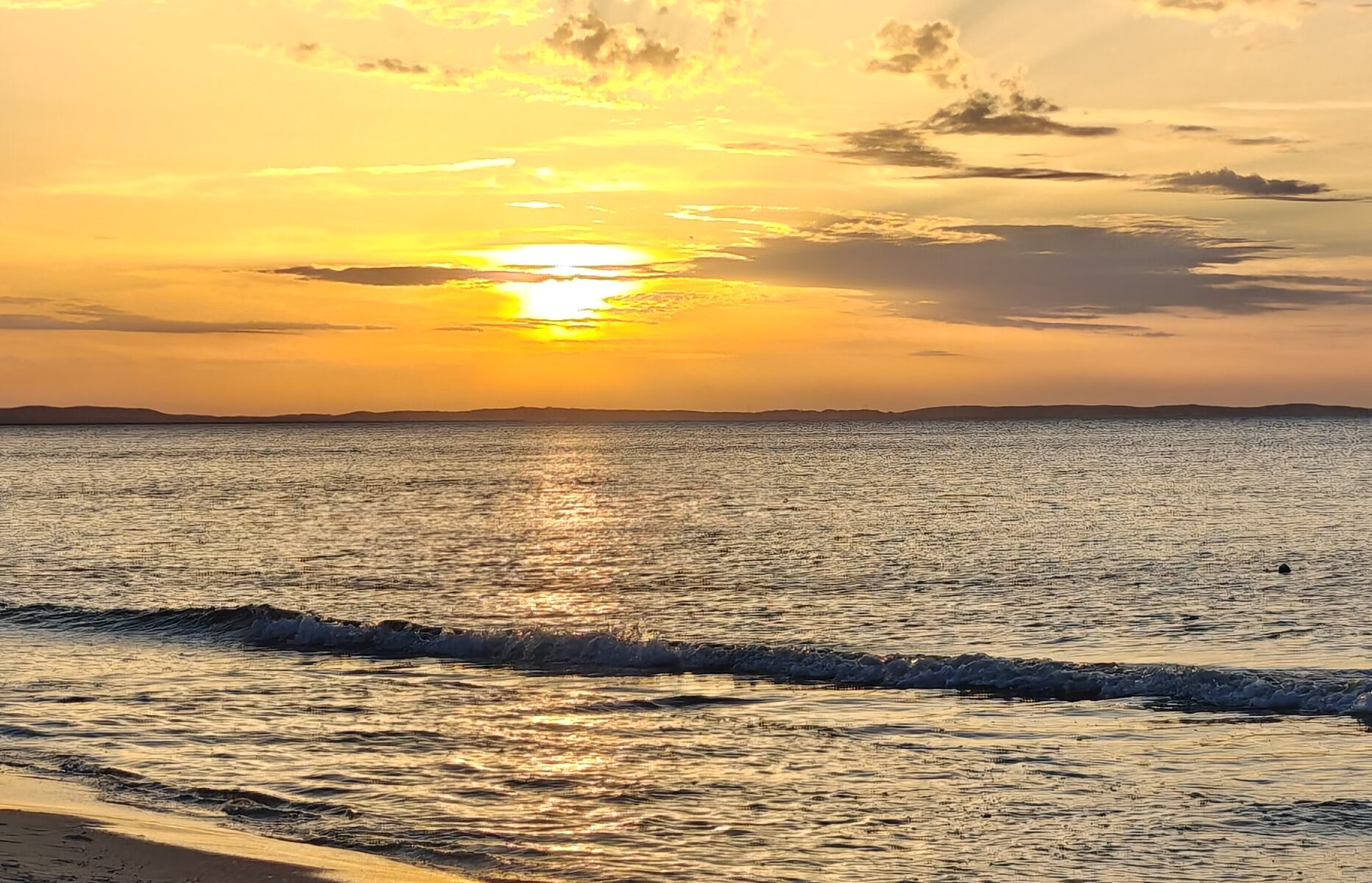 Golden sun rays above a sandy Baltic Sea beach at sunset