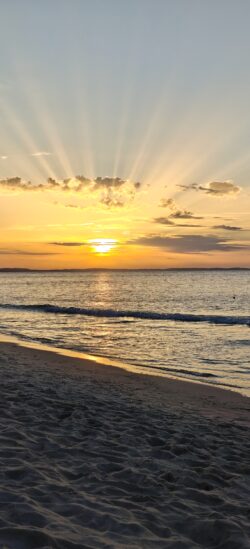 Golden sun rays above a sandy Baltic Sea beach at sunset