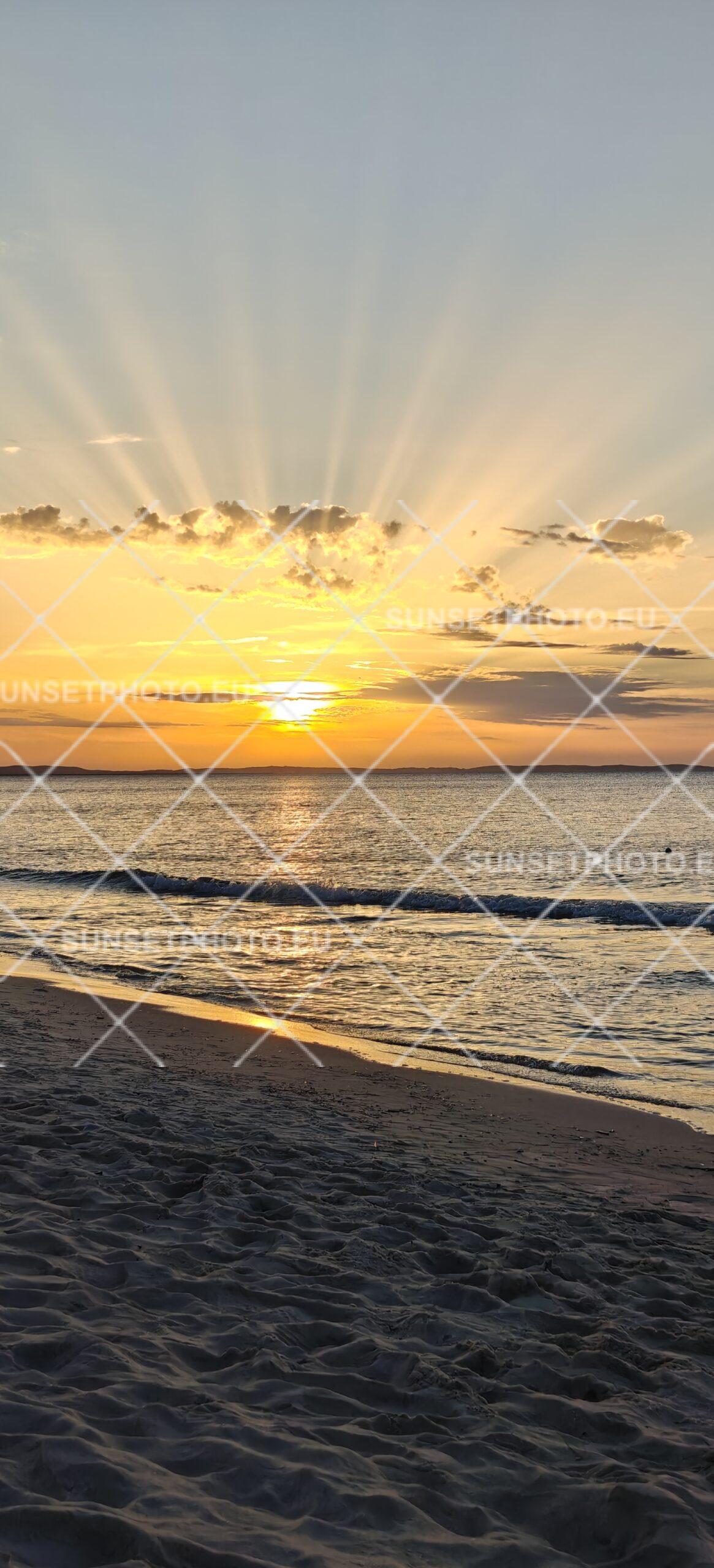 Golden sun rays above a sandy Baltic Sea beach at sunset